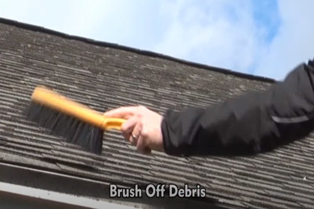 Roof maintenance by worker with a brush