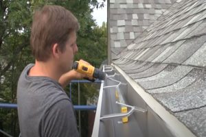 Gutter installation by worker with power tool